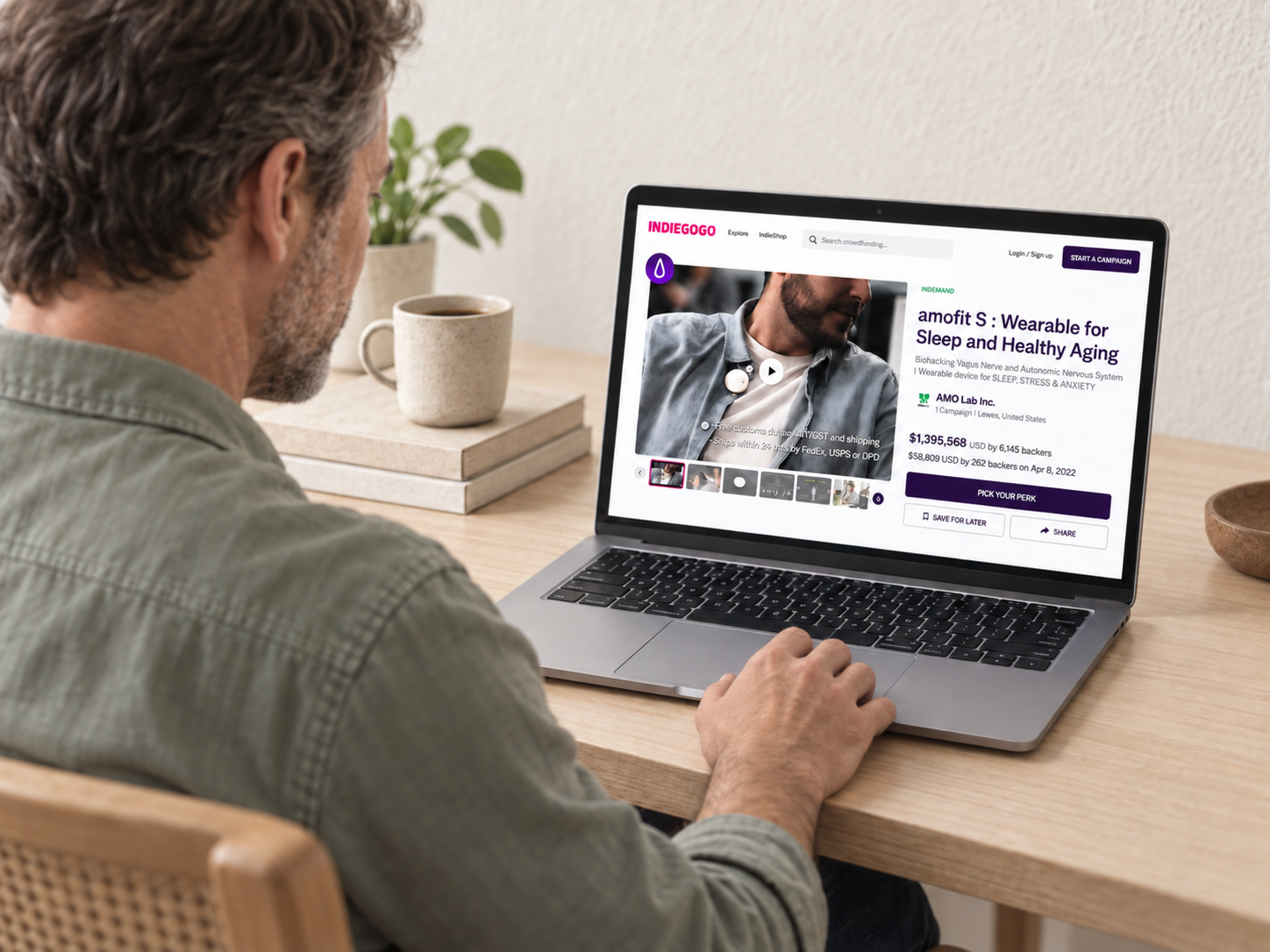 A seated person viewing the original AMOFIT Indiegogo campaign on a laptop